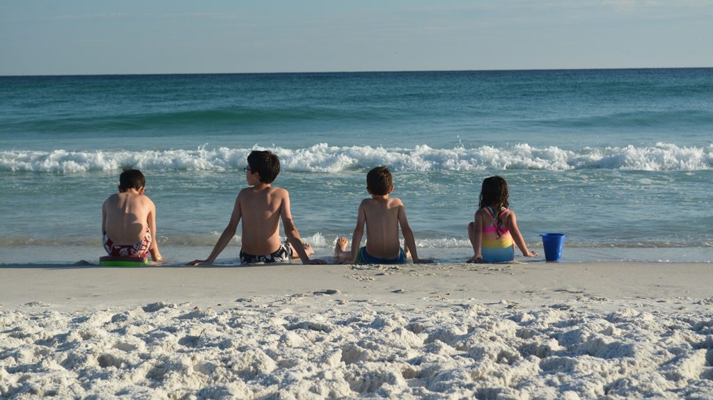 Our kids sitting at the edge of the ocean